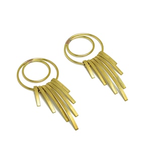 May include: A pair of gold earrings with a circle design and dangling strands of metal.