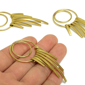 Puede incluir: Pendientes de metal dorado con un diseño en espiral y múltiples barras curvas. Los pendientes tienen una estética vintage y se muestran en un estudio. Un accesorio único.