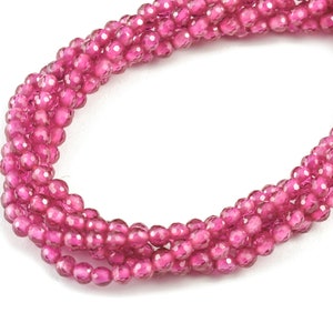May include: A strand of pink faceted gemstone beads. The beads are round and have a smooth, polished finish.