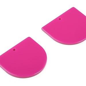 Könnte beinhalten: Zwei rosa halbrunde Formen aus Kunststoff mit einem Loch oben.