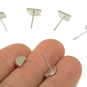 Op de afbeelding: Zilverkleurige oorstekers in verschillende vormen, waaronder halve manen en rechthoeken. De oorbellen worden getoond tegen een witte achtergrond, sommige worden in een hand gehouden. Deze oorbellen zijn een eenvoudige en elegante sieradenoptie.