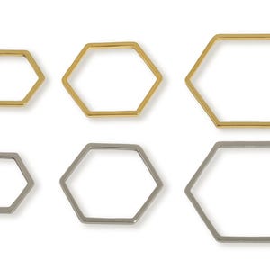 May include: Six open-frame hexagon shapes in gold and silver tones are arranged on a white background. The hexagons vary in size, with three gold and three silver pieces. The shapes are likely jewelry components or design elements.