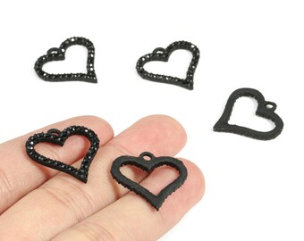 May include: Black heart-shaped charms. Some charms are outlined with small, black rhinestones. The charms have a small loop at the top for attaching to jewelry. The charms are on a white background.