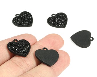 May include: Black heart-shaped pendants. Some pendants are covered in small, sparkling black crystals, while others have a smooth, matte finish. Each pendant has a small loop at the top for attaching to a chain or other jewelry component.
