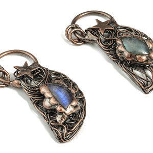 Può includere: Un paio di orecchini in filo di rame con un ciondolo a forma di stella e una pietra preziosa in labradorite blu incastonata in ogni orecchino.