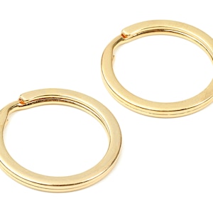 May include: Two gold-colored key rings. The key rings are round and have a smooth finish.