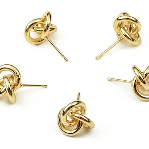 May include: Four pairs of gold knot-shaped stud earrings. The earrings are made of a smooth, shiny metal and have a simple, elegant design.