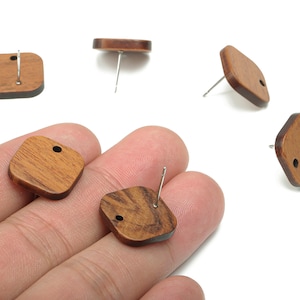 Op de afbeelding: Houten oorstekers in vierkante en ruitvormige vormen. De oorbellen zijn warmbruin van kleur met een zichtbare houtnerf. Elke oorbel heeft een zilveren pin.