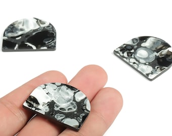 May include: Three black, white, and gray marbled resin pendants in a half-circle shape. The pendants have a flat back and a slightly domed front. One pendant is held in a hand.