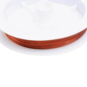 May include: A spool of copper wire wound around a white plastic bobbin. The wire is a bright orange-red colour.