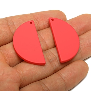 May include: Two red, semi-circular earring components with a small hole at the top for attachment. The components are smooth and matte, and are displayed against a neutral background.