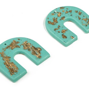 May include: Two turquoise blue arch-shaped earrings with gold leaf accents.
