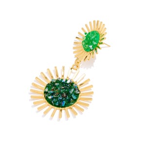 Op de afbeelding: Goudkleurige oorbellen met een sunburst-ontwerp. Elke oorbel heeft een centrale cluster van groene en iriserende stenen. De oorbellen hebben een stekersluiting en zijn geplaatst tegen een witte achtergrond.