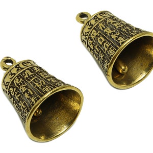 Pode incluir: Dois sinos dourados com desenhos intrincados e um pequeno badalo no interior. Os sinos têm um laço na parte superior para pendurar.