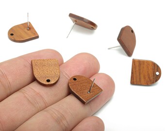 May include: Wooden stud earrings in various shapes, including a half-circle and a teardrop. The earrings are a warm brown color with a visible wood grain. Each earring has a silver-colored post for piercing.