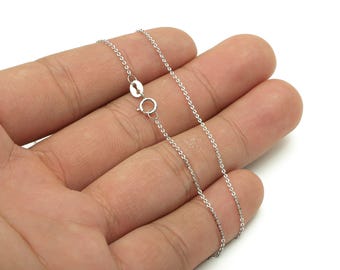 May include: A delicate silver chain necklace with a lobster clasp, displayed on a hand against a white background. The chain is thin and appears to be made of small, interconnected links. The clasp is open, ready to be fastened.