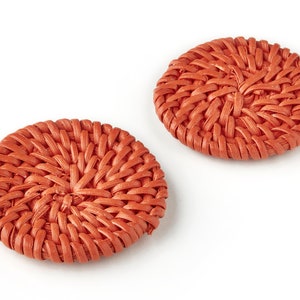 May include: Two round, orange woven coasters. The coasters are made of a woven material that resembles wicker.