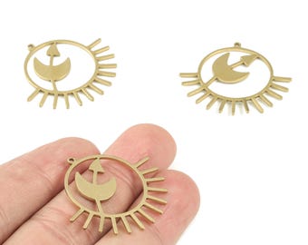 May include: Gold-colored metal pendants featuring a celestial design. Each pendant has a circular frame with sun ray-like extensions and a central design of a crescent moon and arrow. The pendants are shown against a white background.