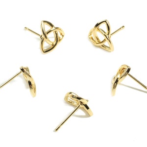 May include: Four gold-toned earrings with a knot design. The earrings are in the shape of a triangle with a knot in the center. The earrings are on a white background.