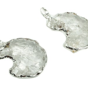 Può includere: Due ciondoli d'argento con cristalli di quarzo trasparenti. I cristalli hanno una forma irregolare e una texture ruvida e naturale. I ciondoli sono attaccati ad anelli di salto d'argento.