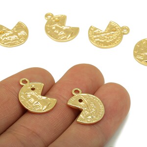 May include: Gold-coloured metal charms in a Pac-Man shape, with a textured surface and a small loop for attaching to jewellery. Several charms are scattered on a white background, with two held in a hand.