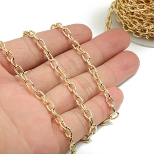 May include: A gold chain with oval links. The chain is lying on a hand.