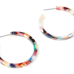 Könnte beinhalten: Ein Paar bunte Creolen mit Marmorierung. Die Ohrringe sind aus Kunststoff und haben einen silberfarbenen Stift.