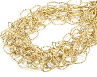 May include: A gold-colored necklace composed of numerous intertwined, textured chains. The chains are arranged in a layered, overlapping pattern, creating a dense and intricate design. The necklace is set against a white background.
