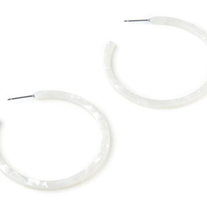 Peut inclure: Une paire de boucles d'oreilles créoles blanches avec un effet marbré.