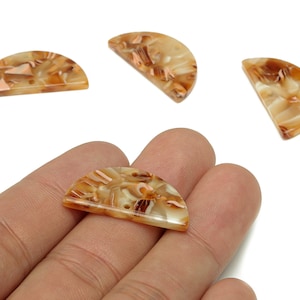 Puede incluir: Cuatro cuentas de resina en forma de semicírculo, veteadas en tonos beige, marrón y crema. Las cuentas tienen un acabado brillante y se muestran sobre un fondo blanco. Estas cuentas son ideales para la fabricación de joyas.