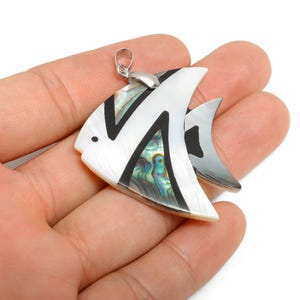 May include: A fish-shaped pendant with a silver bail. The pendant features a white shell body with black accents and iridescent abalone shell details. The fish has a small black dot for an eye.