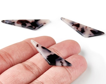 Puede incluir: Tres cuentas triangulares alargadas con un patrón de carey en negro, marrón y crema. Una cuenta se sostiene en una mano, mientras que las otras dos están colocadas cerca. Las cuentas tienen un acabado brillante y un agujero en el extremo estrecho.