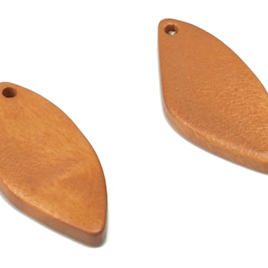 May include: Two wooden leaf-shaped pendants with a hole at the top for hanging. The pendants are a light brown color.