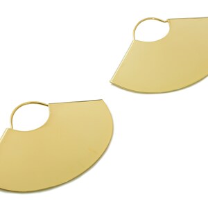 May include: A pair of gold hoop earrings with a semi-circular design. The earrings are made of a smooth, shiny metal.
