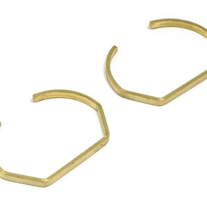 May include: Two gold-toned metal bracelets with a hexagonal shape.