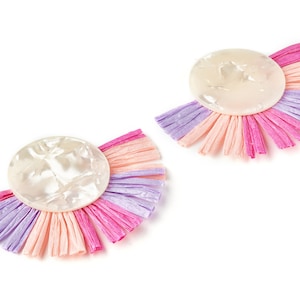 May include: A pair of earrings with a white, round, textured, shell-like centre and a fringe of pink, peach, and lavender fabric.
