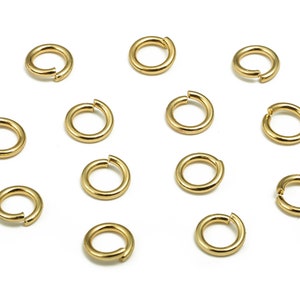 Op de afbeelding: Een set van 14 gouden springringen. De ringen zijn allemaal even groot en zijn in een cirkel op een witte achtergrond gerangschikt.