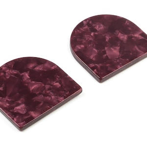 May include: Two burgundy-colored, semi-circular, resin earrings with a marbled pattern.