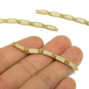 Può includere: Maglie di catena di gioielli color oro con un motivo ripetuto di segmenti rettangolari. Ogni segmento è riempito di piccole pietre trasparenti. Le maglie sono esposte su sfondo bianco, con una catena tenuta in mano.