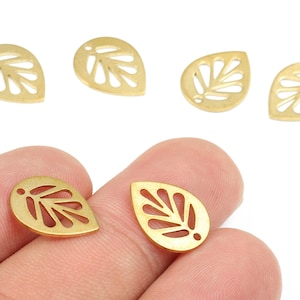 May include: Gold-coloured leaf-shaped charms with a cut-out leaf vein design. The charms are teardrop-shaped with a small hole at the top for stringing. The charms are shown against a white background.