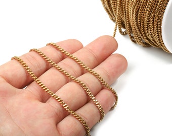 May include: A close-up of a gold chain, with three strands of the chain lying on a hand. The chain is made of small, linked metal pieces.