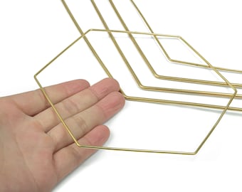 以下が含まれることがあります： 手は、金色の幾何学的なワイヤーフレームを持っています。ワイヤーフレームは六角形で、背景には同様の形状がいくつかあります。ワイヤーは細く、金属製のように見えます。