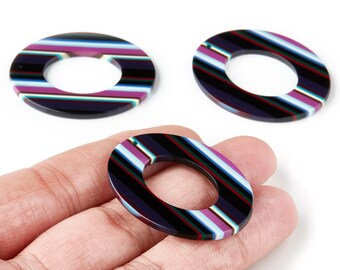 May include: Three oval-shaped resin beads with a striped pattern in black, purple, white, and red. The beads have a hole in the center and are displayed on a white background.
