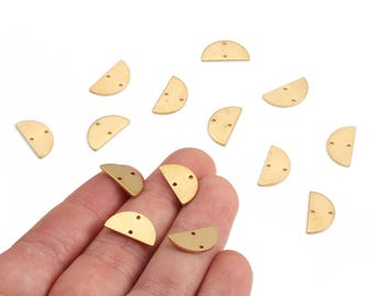 May include: Gold-colored, half-moon shaped metal jewelry findings with three small holes. Several pieces are scattered on a white surface, with some held in a hand. These findings are ideal for jewelry making.