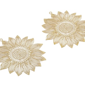 May include: Two gold metal sunflower-shaped charms with intricate cut-out designs. The charms have a hole at the top for attaching to jewelry or other crafts.