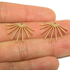 May include: Two gold-colored, sunburst-shaped earring components. Each component has a small hole at the top and eight straight, radiating lines. The earrings are displayed against a neutral background.