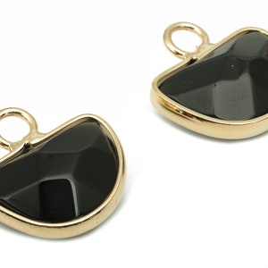 Può includere: Due ciondoli in metallo dorato con inserti in vetro nero sfaccettato. Ogni ciondolo ha un anello nella parte superiore per essere attaccato a una collana o un braccialetto.