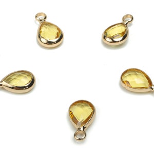 Puede incluir: Cinco abalorios de oro en forma de lágrima con piedras de cristal facetadas de color amarillo claro. Los abalorios tienen un bucle en la parte superior para sujetarlos a joyas.