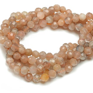 May include: A strand of light brown sunstone beads with a faceted finish. The beads are strung on a clear elastic cord.