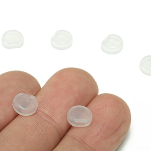 Peut inclure: Plusieurs petits composants ronds en plastique translucide. Ces composants ont une forme légèrement bombée avec une base plate et une petite encoche. Ils sont probablement utilisés comme capuchons ou couvercles de protection.